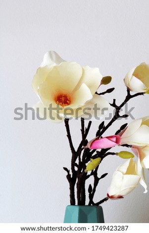 fabric magnolia in a decorative vase against a white background