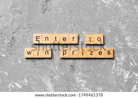 Enter to win prizes word written on wood block. Enter to win prizes text on cement table for your desing, Top view concept.