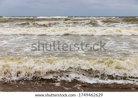 Dirty sea waves hitting the beach in stormy weather