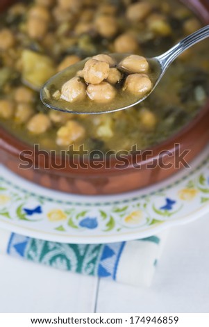 Stew of chickpeas and spinach with cod on a  table with a tablecloth