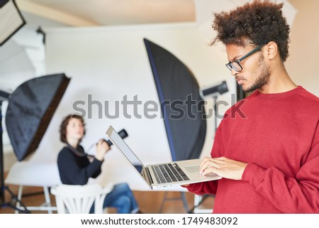 Photographer or photo assistant with laptop computer is planning a photo shoot
