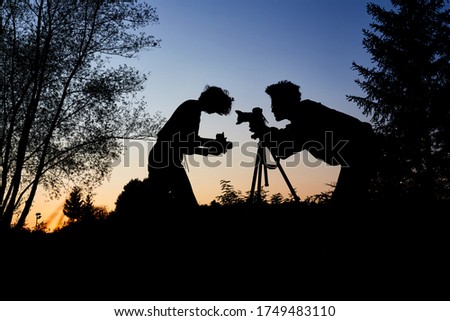 Young couple as hobby photographers take portrait photos at dusk