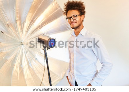 Young man as a model or photographer in front of studio lamp with flashlight