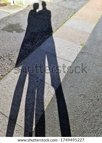 Sun Shadows of man and woman mirroring on sidewalk