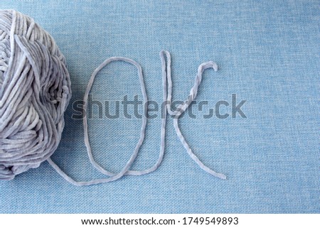 Yarn for knitting on a blue background. Of the threads the letters OK are written. Concept photo to do your favorite thing.