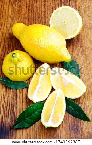 Fresh Ripe Lunario Lemons Full Body and Halves with Leafs closeup on Wooden background Royalty-Free Stock Photo #1749562367
