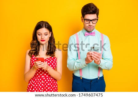 Photo of pretty lady handsome guy hold telephone hands careless people browsing addicted users wear red dotted dress shirt bowtie isolated yellow bright color background