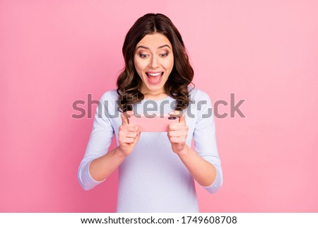 Photo of beautiful attractive lady hold telephone hands stay home quarantine time playing online video game excited good mood wear casual white shirt isolated pastel pink color background
