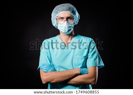 Photo of nurse guy expert family doc covid19 protection control arms crossed wear mask blue uniform suit gown t-shirt plastic facial goggles surgical cap isolated black color background Royalty-Free Stock Photo #1749608855