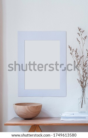 Mockup wooden bowl on wooden table with blank picture frame on the wall.