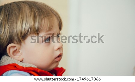Little kid with blue eyes while watching TV. Young boy watch television in living room. Child watching TV, close up face of little boy.
