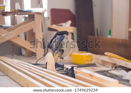A pieces of a wood girder and a circular saw. A flat repair process. Indoor photo