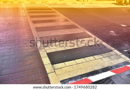 The white solid line crosswalk between brick road and asphalt road. Pedestrian crossing on the old macadamized road with retro colour light at Phuket island, Thailand. Safely walk across the road.