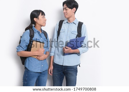 Photo of a cheery loving couple friends students isolated over white background holding books.with backpack

