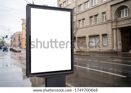 advertising city billboard, with a white field for advertising near the road on a rainy day