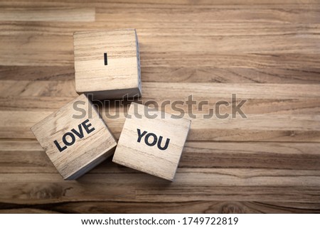 "I Love You" text on the wooden cubic block that placed on the wooden texture, with copy space for. Velentine or marry abstract concept. Selective focus on the text. 