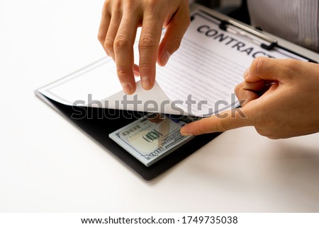Bribery and corruption concept, businessmen offer bribes in the form of dollar bills To sign the contract by hiding the money while making the agreement
