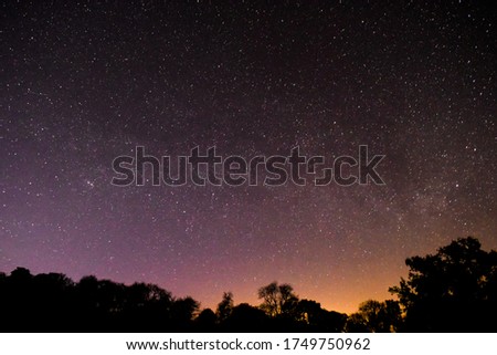 Beautiful vibrant summer countryside landscape shot of the Milky Way deep in the Brecon Beacons with silhouette tree line.
