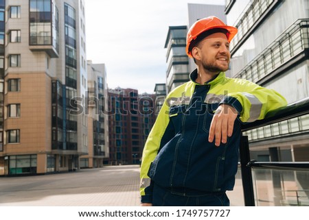 young handsome smiling architect holding construction supervision drawings.