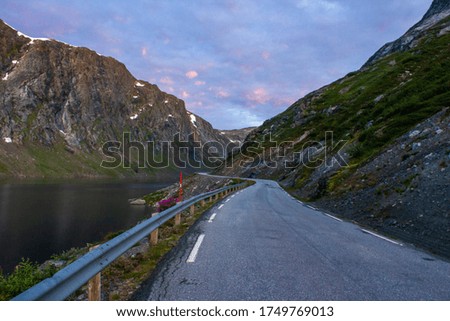 Morning on the road. Mountain view with snow and a beautiful lake. At the top of the mountain lies snow. Norway