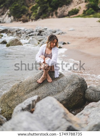 Girl with white shirt sitting on a rock