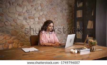 A business woman is working in the office with a computer.