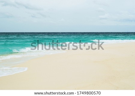 Clean beach in summer, Sea wave with white foam, rainy sky for background, backdrop and wallpaper with copy space for text, Relaxing vacation and business travel concept