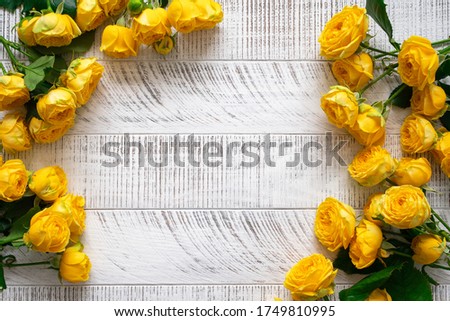 Yellow roses on the white wooden background. Top view. Copy space.