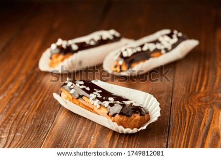 Traditional fresh dessert eclair with chocolate on wooden background