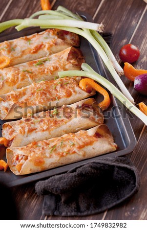 Homemade and healthy enchiladas. Mexican cuisine. Tortilla with vegetables and chicken meat.