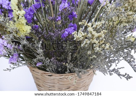 Purple dried Caspia, Statice, Lavender, The Yellow Eyed Grass (Xyridaceae Flower) and Barley Rice in the rattan pot on the white background