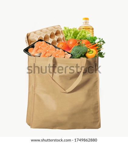 Eco-friendly reusable shopping bag filled with different goods on a white background