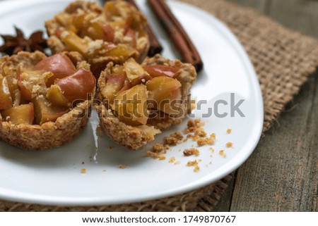 Crispy small tartlets made from shortcrust pastry with apples, homemade sweets with anise and cinnamon. Top view, gunny on a wooden background. Rustic style. Eco sweets concept, warm cozy tea party