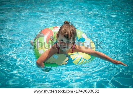 Portrait of pretty happy little girl in the swimming pool. Funny kid playing outdoors. Summer vacation concept. Horizontal image.