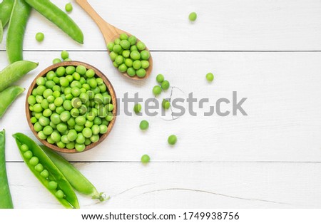 Fresh green peas with pod in bowl and spoon on white wooden table, healthy green vegetable or legume ( pisum sativum ) Royalty-Free Stock Photo #1749938756