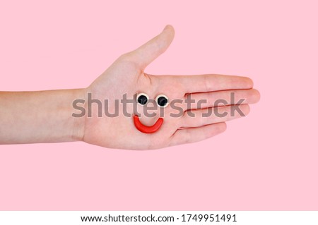 Hand on a pink background with a smiling emoticon. Good mood concept