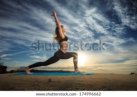 Woman practicing Warrior yoga pose outdoors over sunset sky background.  Royalty-Free Stock Photo #174996662