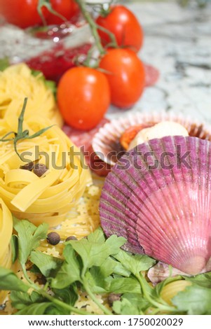 Image of ingredients of italian pasta seafood. Illustration for culinary blogs. Pasta, scallops, tomatoes, greens. Picture with selective focus.