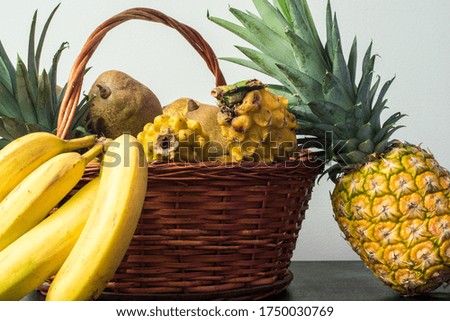 Still life of different yellow fruits like pitaya, banana and pineapple on a wooden surface