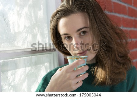 Young woman with a cup of tea by the winter window