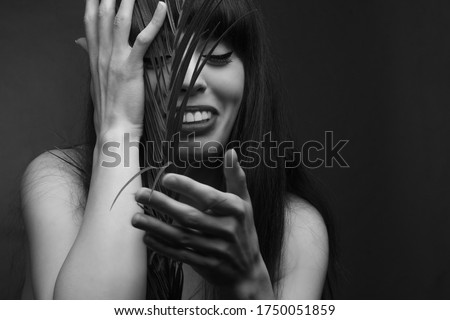 black and white portrait of a young woman with leaf palms. Studio photo