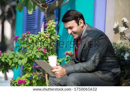 Young businessman doing work on tablet outside of an office building.