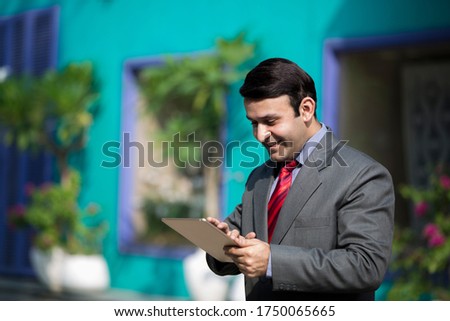 Young businessman doing work on tablet outside of an office building.