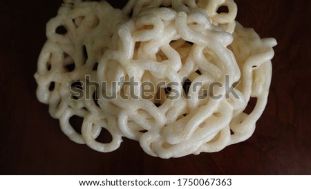 Krupuk or kerupuk or kroepoek is an Indonesian deep fried crackers made from starch and other ingredients that serve as flavouring. Close Up Top View Real Photo on wooden background