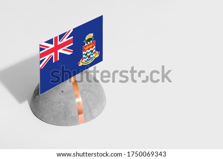 Cayman Islands flag tagged on rounded stone. White isolated background. Side view minimal national concept.