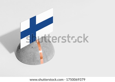 Finland flag tagged on rounded stone. White isolated background. Side view minimal national concept.
