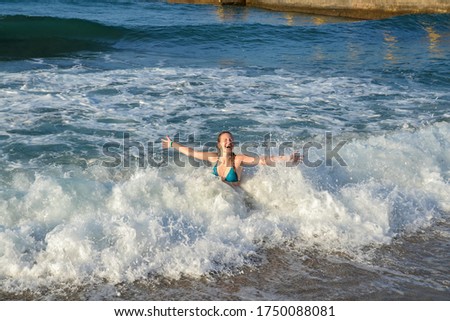 A young happy girl splashing in the sea waves. Vacation on the Mediterranean Sea.