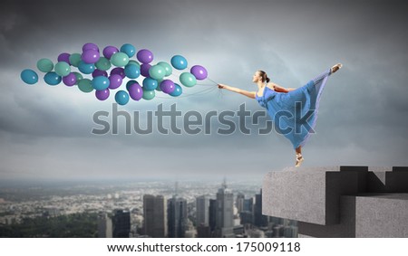 Young woman in dress and ballerinas dancing with colorful balloons