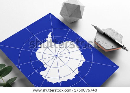 Antarctica flag on minimalist paper background. National invitation letter with stylish pen on stone. Communication concept.