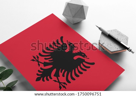 Albania flag on minimalist paper background. National invitation letter with stylish pen on stone. Communication concept.